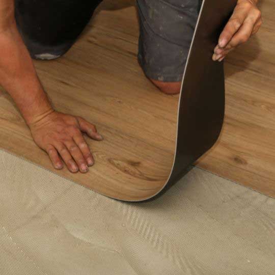 Professional installer laying LVT flooring with precision.